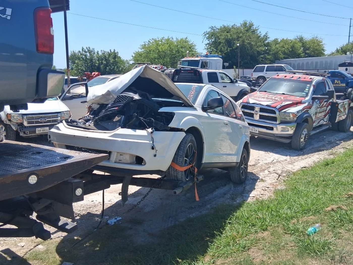 Camioneta con el frente destrozado esperando en el lote junto a las grúas